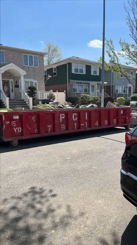 A red dumpster was parked in front of the house of a residential Manhattan dumpster rental service. Photo taken January 2024.