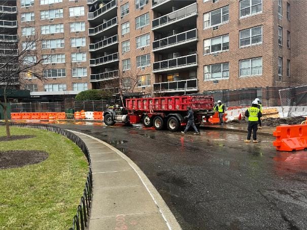 Construction Bins: Enhance your construction project with our reliable Construction Bins. Witness skilled workers building a tall structure on a bustling street. Photo taken March 2024.
