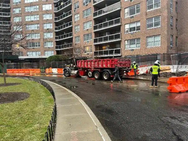 Construction Bins: Enhance your construction project with our reliable Construction Bins. Witness skilled workers building a tall structure on a bustling street. Photo taken March 2024.