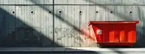 a vibrant red dumpster prominently displayed against the sleek concrete backdrop of an urban construction site, emblazoned with the pci logo, symbolizing efficiency and value in waste management solutions.