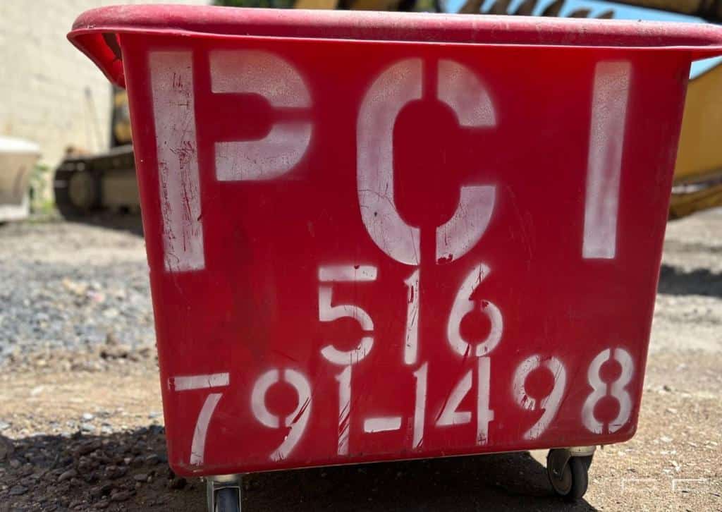 Close-up of a dumpster with permit tags near a municipal building